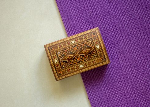 Top view of a wooden box very well ornamented with small bamboo pieces, with a white and purple background