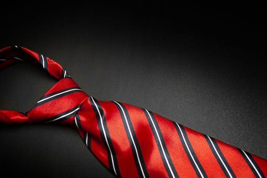 Red men's striped tie isolated on black background