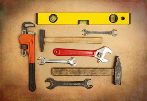 Various tools to work with, hammer, spanner, gas wrench, level to measure the level. Close-up on a background of craft paper