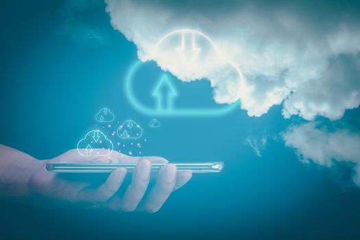 Double exposure of hand holding smartphone with cloud icon on blurry blue sky. Connecting and social network security. Communication of business and financial. Cloud data storage concept.