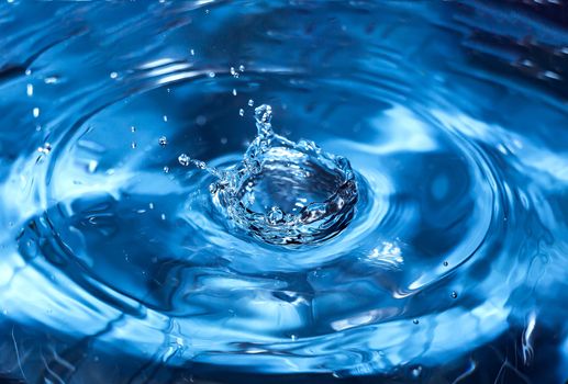 Water splash close-up. Drop of water. Blue water drop. Falling blue water surface with splash and air bubbles