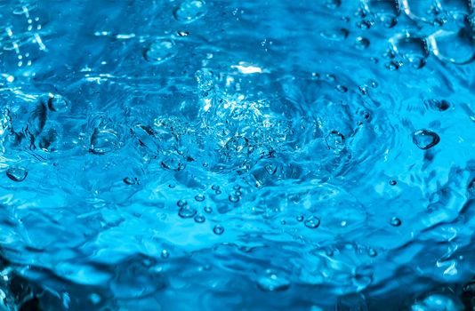 Water splash close-up. Drop of water. Blue water drop. Falling blue water surface with splash and air bubbles