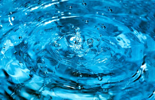 Water splash close-up. Drop of water. Blue water drop. Falling blue water surface with splash and air bubbles