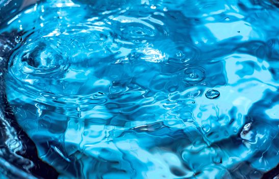 Water splash close-up. Drop of water. Blue water drop. Falling blue water surface with splash and air bubbles