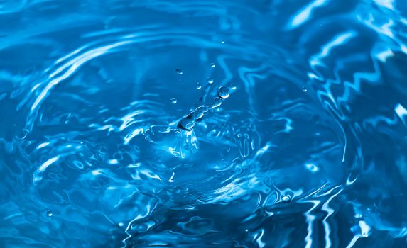 Water splash close-up. Drop of water. Blue water drop. Falling blue water surface with splash and air bubbles.