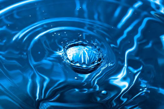 Water splash close-up. Drop of water. Blue water drop. Falling blue water surface with splash and air bubbles.