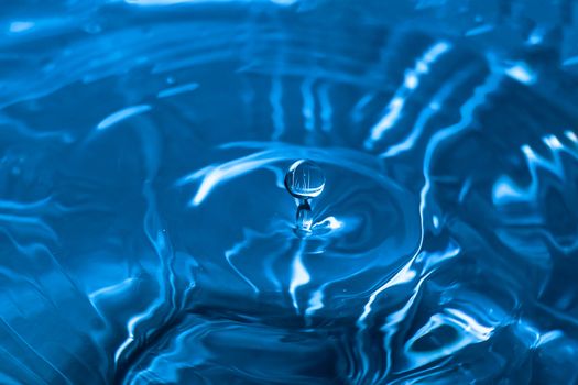 Water splash close-up. Drop of water. Blue water drop. Falling blue water surface with splash and air bubbles