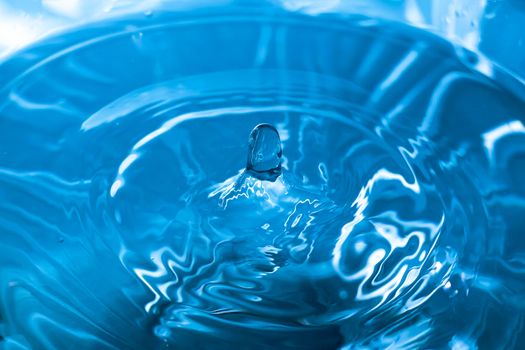 Water splash close-up. Drop of water. Blue water drop. Falling blue water surface with splash and air bubbles