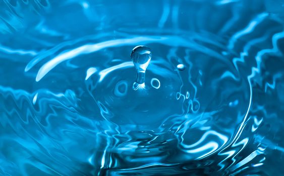 Water splash close-up. Drop of water. Blue water drop. Falling blue water surface with splash and air bubbles