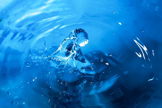 Water splash close-up. Drop of water. Blue water drop. Falling blue water surface with splash and air bubbles