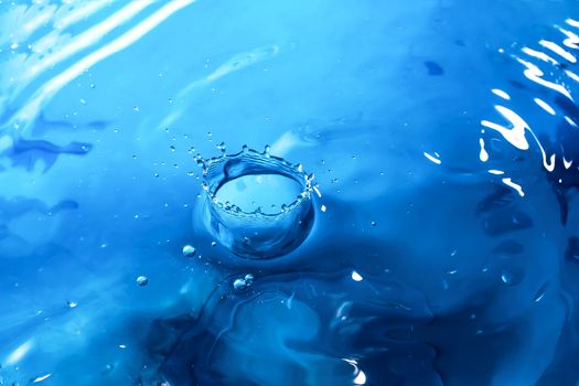 Water splash close-up. Drop of water. Blue water drop. Falling blue water surface with splash and air bubbles