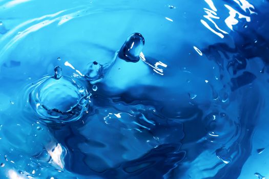 Water splash close-up. Drop of water. Blue water drop. Falling blue water surface with splash and air bubbles.