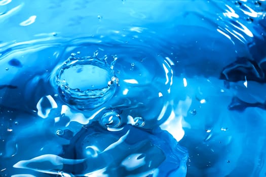 Water splash close-up. Drop of water. Blue water drop. Falling blue water surface with splash and air bubbles