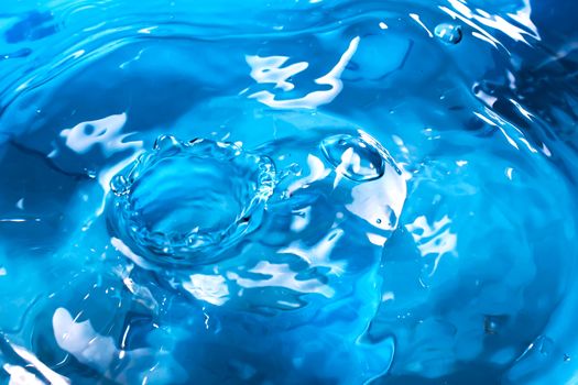 Water splash close-up. Drop of water. Blue water drop. Falling blue water surface with splash and air bubbles