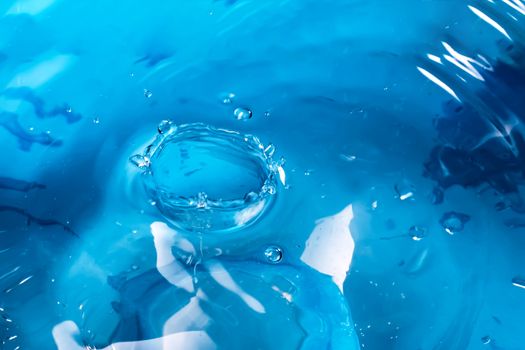 Water splash close-up. Drop of water. Blue water drop. Falling blue water surface with splash and air bubbles