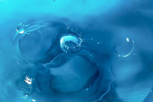 Water splash close-up. Drop of water. Blue water drop. Falling blue water surface with splash and air bubbles