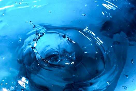 Water splash close-up. Drop of water. Blue water drop. Falling blue water surface with splash and air bubbles