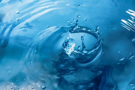 Water splash close-up. Drop of water. Blue water drop. Falling blue water surface with splash and air bubbles