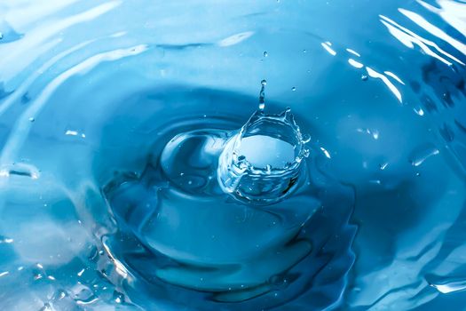 Water splash close-up. Drop of water. Blue water drop. Falling blue water surface with splash and air bubbles