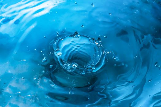 Water splash close-up. Drop of water. Blue water drop. Falling blue water surface with splash and air bubbles