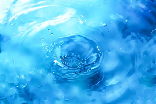 Water splash close-up. Drop of water. Blue water drop. Falling blue water surface with splash and air bubbles