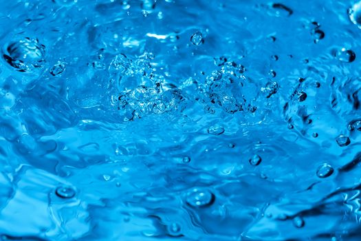 Water splash close-up. Drop of water. Blue water drop. Falling blue water surface with splash and air bubbles