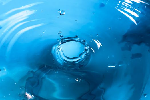 Water splash close-up. Drop of water. Blue water drop. Falling blue water surface with splash and air bubbles