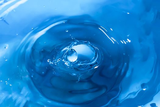 Water splash close-up. Drop of water. Blue water drop. Falling blue water surface with splash and air bubbles