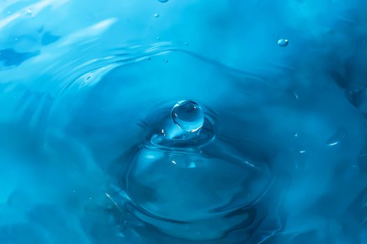 Water splash close-up. Drop of water. Blue water drop. Falling blue water surface with splash and air bubbles