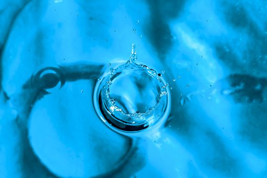 Water splash close-up. Drop of water. Blue water drop. Falling blue water surface with splash and air bubbles