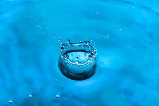 Water splash close-up. Drop of water. Blue water drop. Falling blue water surface with splash and air bubbles