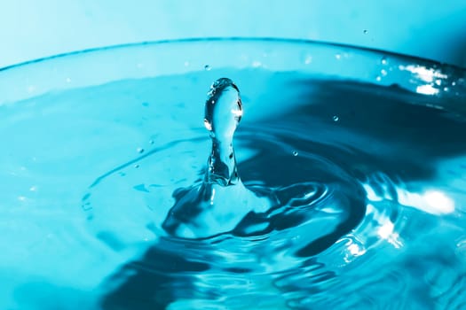 Water splash close-up. Drop of water. Blue water drop. Falling blue water surface with splash and air bubbles