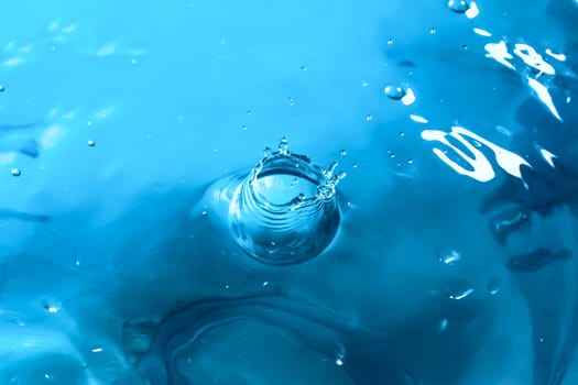 Water splash close-up. Drop of water. Blue water drop. Falling blue water surface with splash and air bubbles