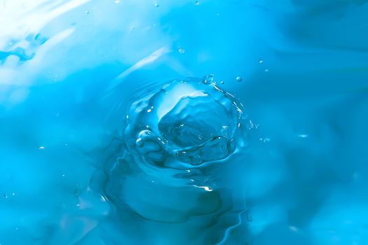 Water splash close-up. Drop of water. Blue water drop. Falling blue water surface with splash and air bubbles