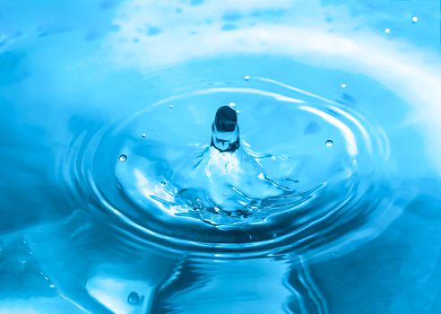 Water splash close-up. Drop of water. Blue water drop. Falling blue water surface with splash and air bubbles