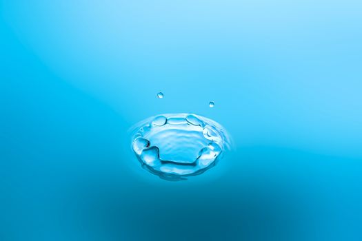 Water splash close-up. Drop of water. Blue water drop. Falling blue water surface with splash and air bubbles