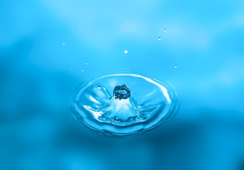 Water splash close-up. Drop of water. Blue water drop. Falling blue water surface with splash and air bubbles