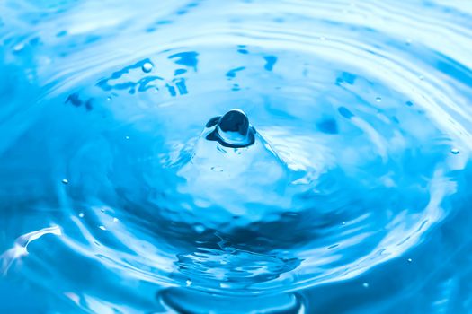 Water splash close-up. Drop of water. Blue water drop. Falling blue water surface with splash and air bubbles