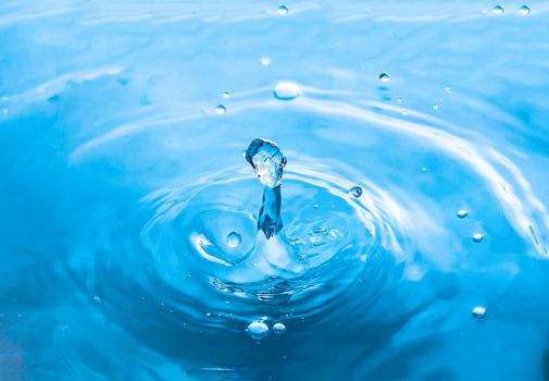 Water splash close-up. Drop of water. Blue water drop. Falling blue water surface with splash and air bubbles