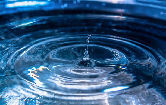 Water splash close-up. Drop of water. Blue water drop. Falling blue water surface with splash and air bubbles