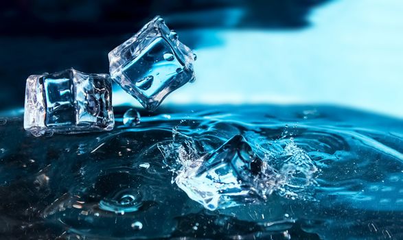 Ice cubes falling into the blue water. Splash of ice water. Water splashes from falling ice cubes.