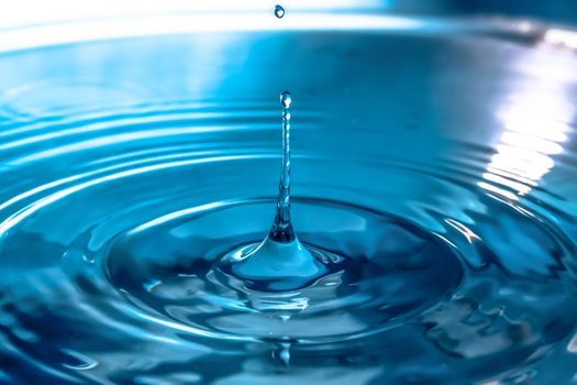 Water splash close-up. Drop of water. Blue water drop. Falling blue water surface with splash and air bubbles