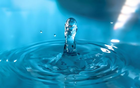 Water splash close-up. Drop of water. Blue water drop. Falling blue water surface with splash and air bubbles