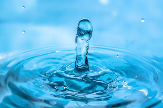 Water splash close-up. Drop of water. Blue water drop. Falling blue water surface with splash and air bubbles