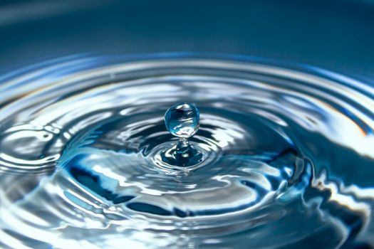 Water splash close-up. Drop of water. Blue water drop. Falling blue water surface with splash and air bubbles