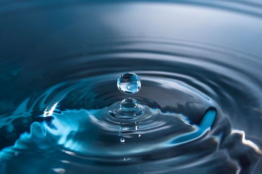 Water splash close-up. Drop of water. Blue water drop. Falling blue water surface with splash and air bubbles