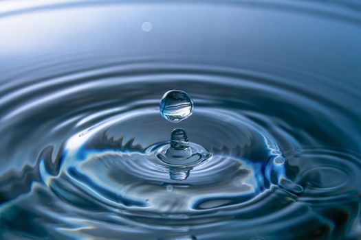 Water splash close-up. Drop of water. Blue water drop. Falling blue water surface with splash and air bubbles