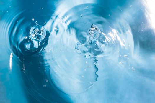 Water splash close-up. Drop of water. Blue water drop. Falling blue water surface with splash and air bubbles