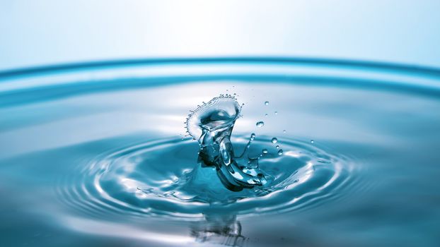 Water splash close-up. Drop of water. Blue water drop. Falling blue water surface with splash and air bubbles