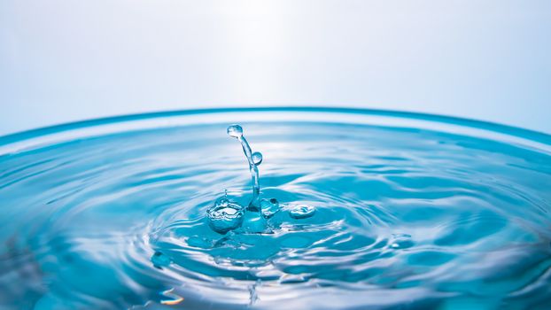 Water splash close-up. Drop of water. Blue water drop. Falling blue water surface with splash and air bubbles